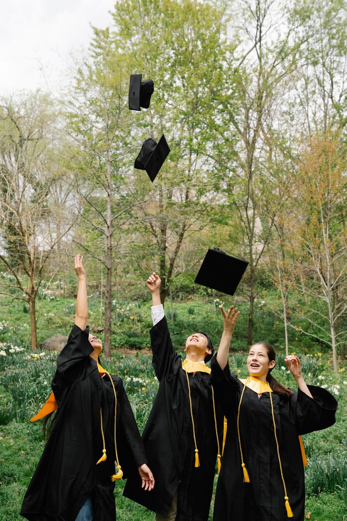 Graduates celebrate by tossing caps in a lively outdoor ceremony.
